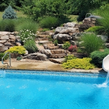 Custom pool slide with waterfall stone steps boulder stone landscaping